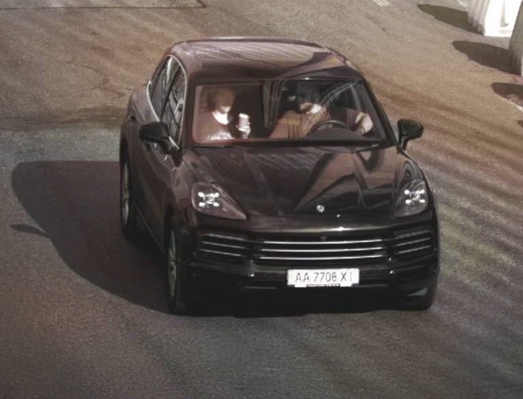 Автомобіль Porsche Cayenne чорного кольору з двома чоловіками у салоні Автомобіль Porsche Cayenne чорного кольору з двома чоловіками у салоні