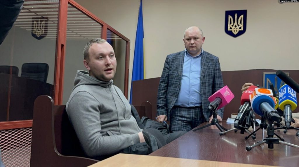 Роман Гринкевич в сером худи сидит рядом со своим адвокатом в зале судебных заседаний Роман Гринкевич в сером худи сидит рядом со своим адвокатом в зале судебных заседаний